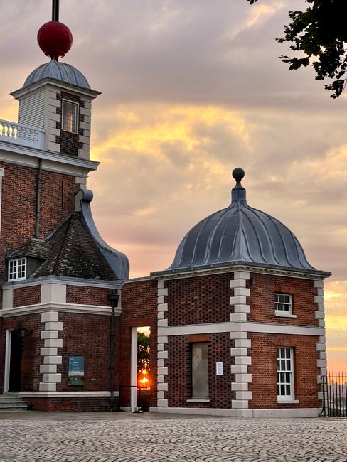 A large, multi-story brick mansion with white-framed windows and ornate architectural details is visible in the background, set within a well-maintained garden featuring a curved stone pathway. The pa